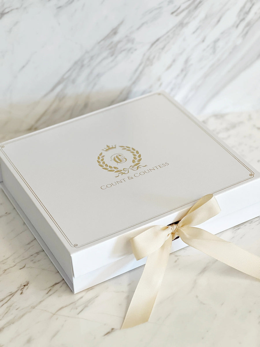Count & Countess signature white gift box with gold crest and satin ribbon