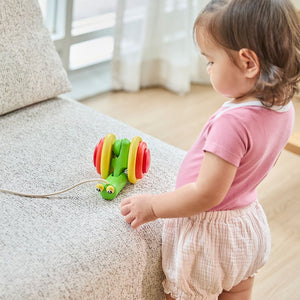 Baby reaching for the PlanToys Pull-Along Snail