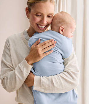 Baby held in Love To Dream Swaddle Up 0.2 TOG Bamboo Mist Blue