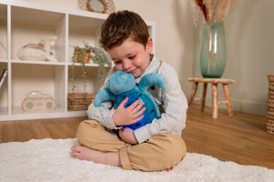 Child holding the Cloud b Tranquil Turtle plush sound soother