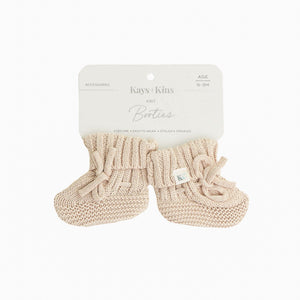 Newborn wearing Kays+Kins beige organic cotton knit booties