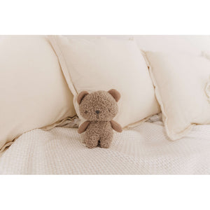 Beanie the Bear knitted plush on a bed