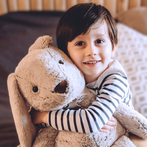 Child cuddling the Histoire d'Ours Copains Calins beige rabbit