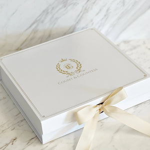 Count & Countess signature white gift box with gold crest and satin ribbon