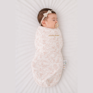 Baby sleeping in the Count & Countess Swaddle Bag, Toile De Jouy Blush