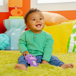 Baby playing with the purple sloth rattle toy