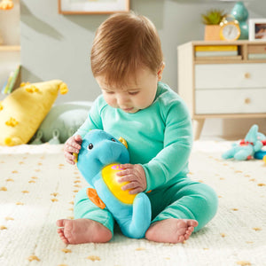 Baby holding the blue Fisher-Price Soothe and Glow Seahorse