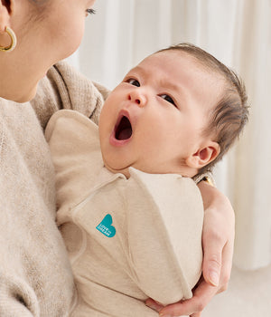Baby held in Love To Dream Swaddle Up 1.0 TOG Cotton Oatmeal